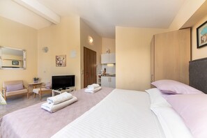 Ein Hotelzimmer mit Bett, Fernseher, Schreibtisch mit Stuhl, einem kleinen Tisch und einer Couch.