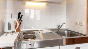 Et moderne køkken med indbygget komfur, vask og hvide skabe.