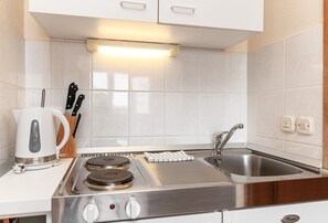 A modern kitchen with a built-in stove, a sink, and white cabinets.