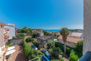Un quartier résidentiel avec vue sur la mer, des maisons aux toits recouverts de tuiles rouges et un palmier.