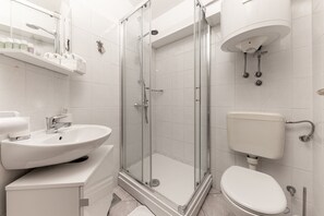 A modern bathroom with a glass-enclosed shower, a white sink, and a toilet.