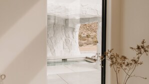 Un intérieur moderne avec une grande fenêtre, un vase rempli de fleurs séchées et une décoration minimaliste.