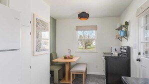 Ett kompakt kök med ett matbord, en bänk och ett kylskåp.