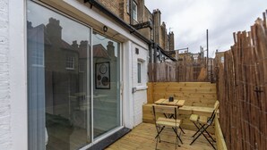 A wooden deck with a table and chairs, a sliding glass door, and a wooden fence.
