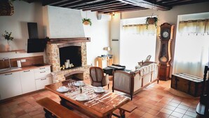 A rustic kitchen with a stone fireplace, wooden table, and chairs.