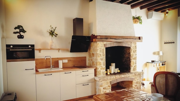 A kitchen with a stone fireplace, wooden cabinets, a built-in oven, and a dining table set with dishes.