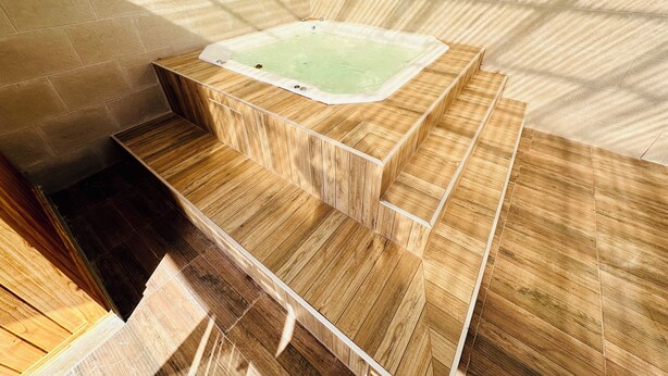 Une salle de bain moderne avec une baignoire sur pieds, des marches en bois et un mur recouvert de carreaux.