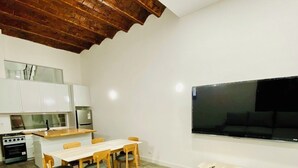 Un salon moderne avec un plafond en bois, un coin repas et une cuisine.