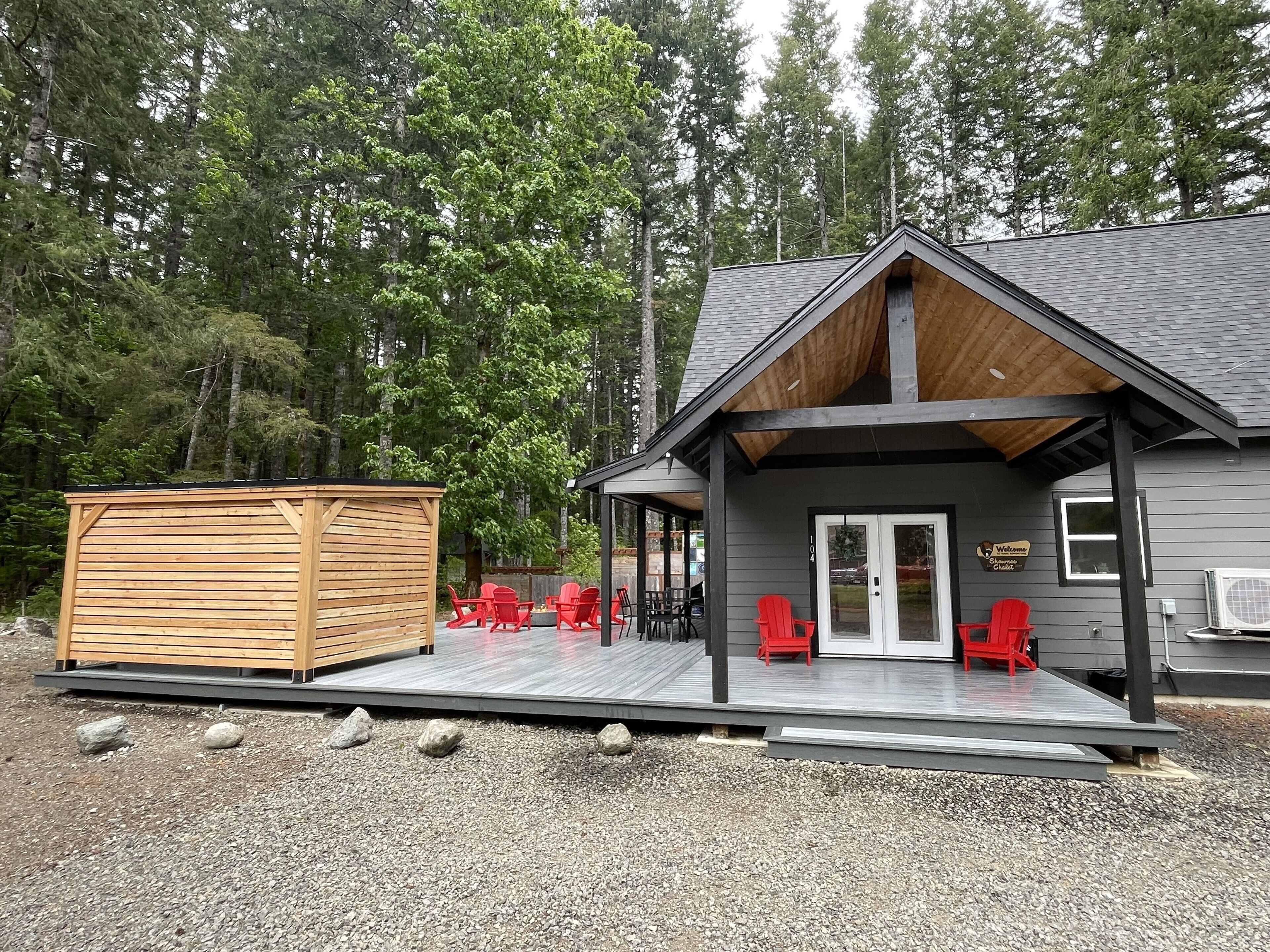 Une cabane dotée d’un porche couvert, de chaises rouges et d’une terrasse en bois.