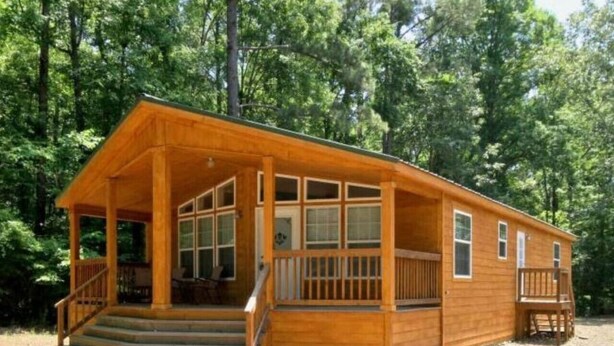 A wooden cabin with a porch, multiple windows, and a staircase leading to the entrance.