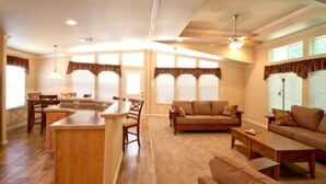 A spacious living room with a large sofa, a coffee table, and a dining area with a bar.