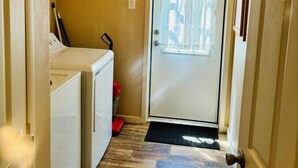 A laundry room with a washing machine, dryer, and a shelf with cleaning supplies.