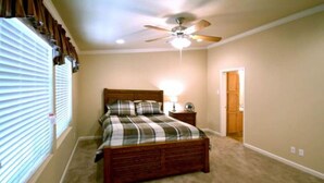 A bedroom with a wooden bed, a ceiling fan, a nightstand, and a window with blinds.