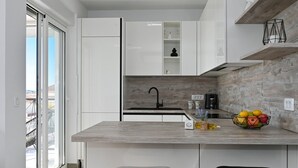 Una cocina moderna con armarios blancos, encimera de madera, grifo negro y un frutero.