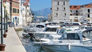 Un puerto deportivo con barcos amarrados, un edificio de piedra y un cielo despejado.
