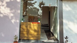 A hotel entrance with a reception desk, a blue sign reading "HOTEL ATHARV INN", and potted plants outside. - Hotel Atharv Inn (Indore)
