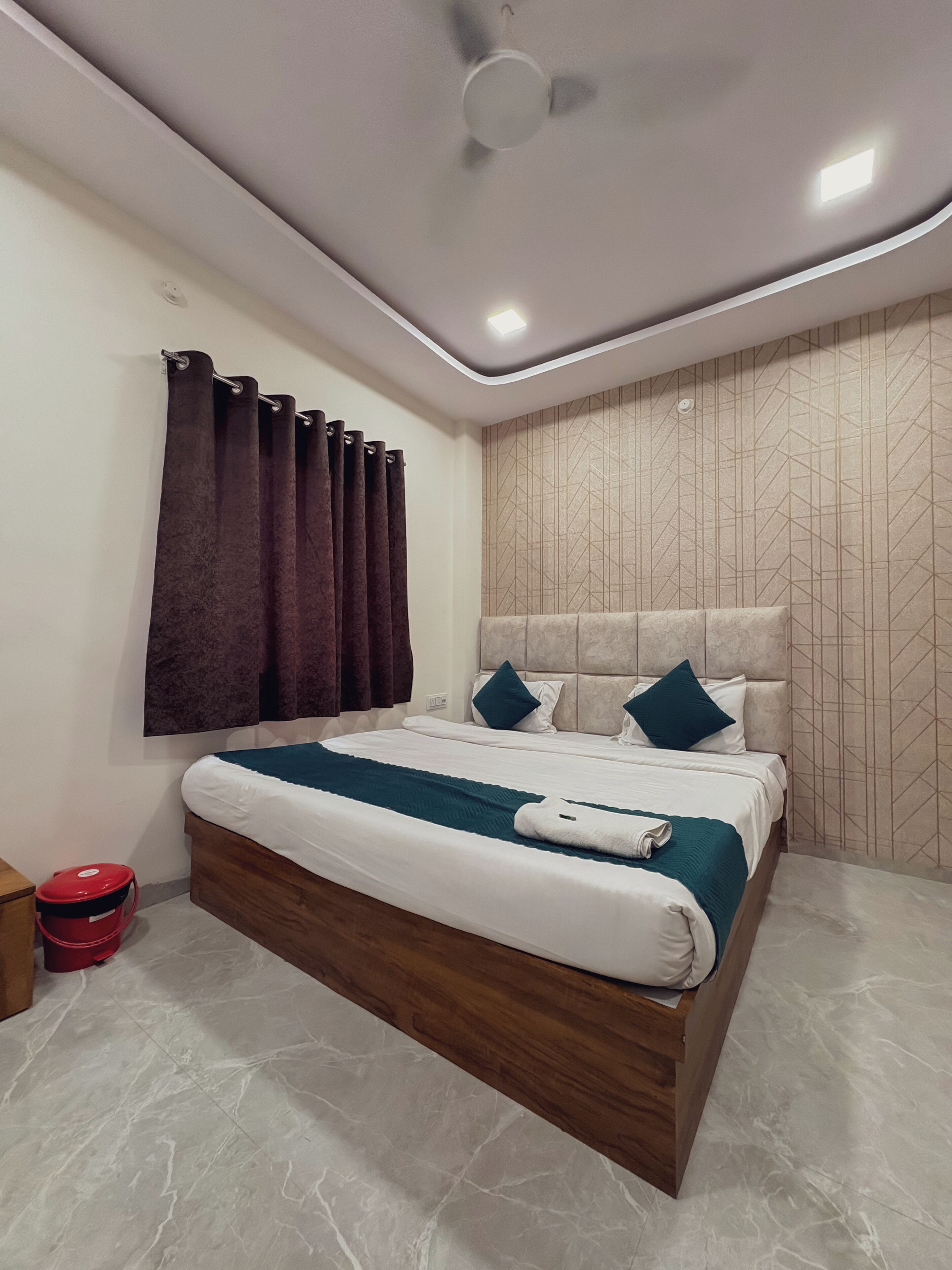 Une chambre à coucher moderne avec un cadre de lit en bois, une tête de lit ornée d’un motif géométrique et un ventilateur de plafond.