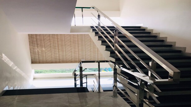 A modern staircase with metal railings and a geometric patterned wall in the background. - Hotel Atharv Inn (Indore)