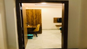 A room with a wooden desk, a chair, a television mounted on the wall, and a tiled floor. - Hotel Atharv Inn (Indore)