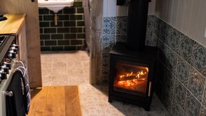 A kitchen with a wood-burning stove, a sink, and patterned tiles. - If you go into the woods today... Off-grid yet comfy, warm and luxurious  (Canterbury)