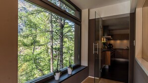 A modern kitchen with a large window overlooking a forest. - Chalet Les Ecureuils (Zermatt)