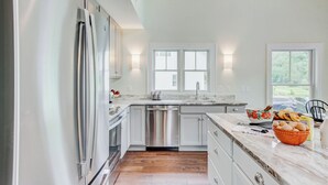 Una cucina moderna con elettrodomestici in acciaio inossidabile, lavastoviglie e un piano di lavoro in marmo.
