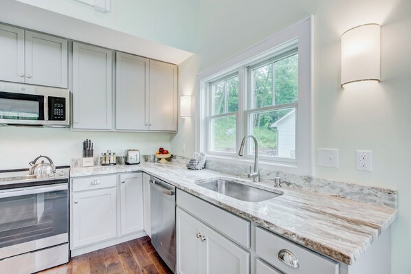 A modern kitchen with white cabinets, a stainless steel oven, a dishwasher, and a marble countertop. - Next to the Springs! Bright + Modern Getaway w/ Mtn Views (Warm Springs)