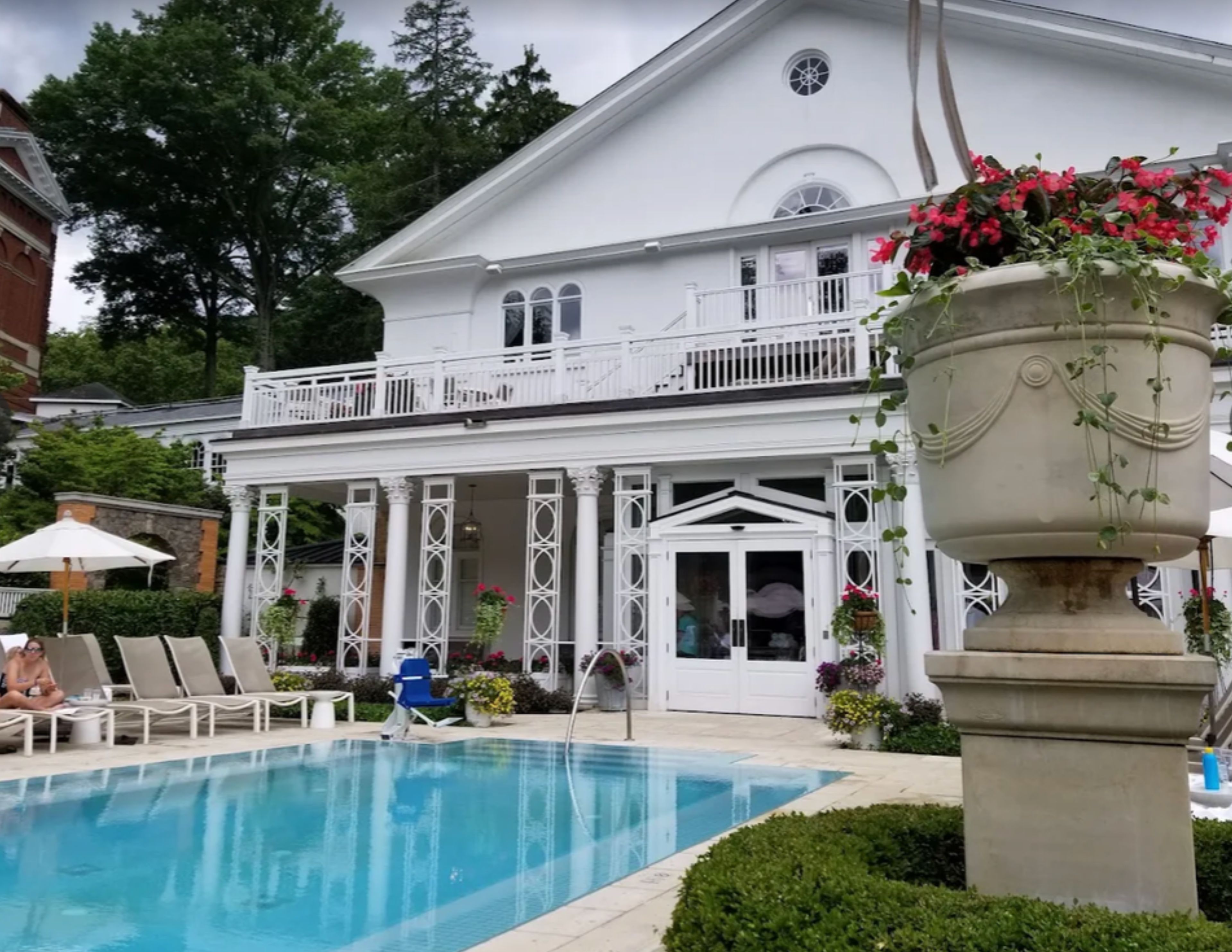 A pool area with lounge chairs and a large planter with flowers.