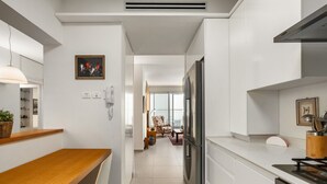 A modern kitchen with white cabinetry, a stainless steel refrigerator, and a wooden dining table.
