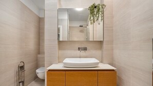 Un baño moderno con un espejo grande, un lavamanos blanco y un inodoro.