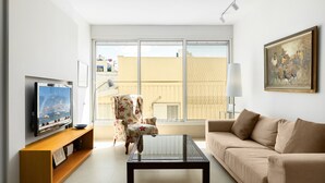 A modern living room with a flat-screen TV, a sofa, a coffee table, and a chair.