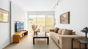 Una sala de estar con sofá, mesa de centro, televisor y una silla.