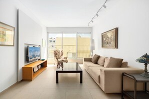 A living room with a sofa, a coffee table, a TV, and a chair.