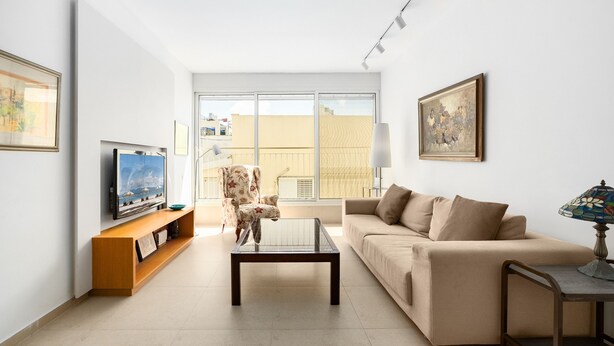 A living room with a sofa, a coffee table, a TV on a stand, a chair, and a lamp.