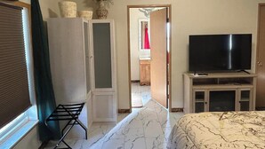 A bedroom with a bed, a television, a wardrobe, and a bathroom visible through an open door. - Spacious Peaceful 2-bedroom home in Saint Ignatius, Montana with amazing views. (Saint Ignatius)