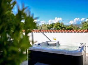 Un jacuzzi sur un toit, avec un ciel bleu dégagé et un toit recouvert de tuiles rouges.