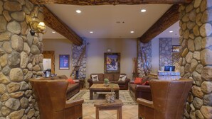 A stone-walled living room with leather furniture, a wooden coffee table, and a painting on the wall.
