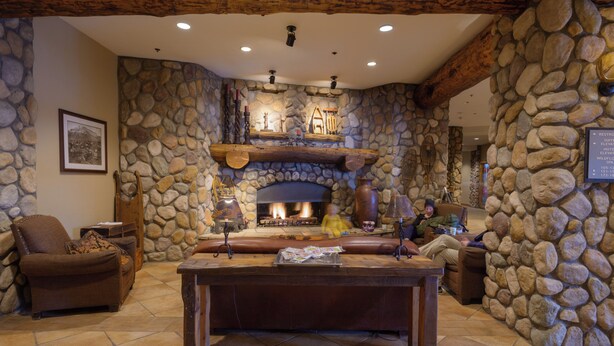 A stone-walled living room with a fireplace, leather seating, and a wooden coffee table.