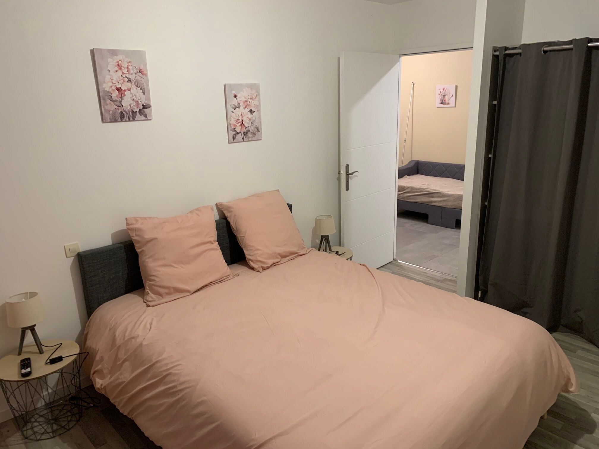 Ein Schlafzimmer mit einem Bett, zwei Kissen, einem Nachttisch mit Lampe und zwei Wandbildern.