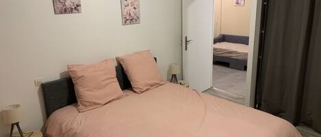 Ein Schlafzimmer mit einem Bett, zwei Kissen, einem Nachttisch mit Lampe und zwei Wandbildern.