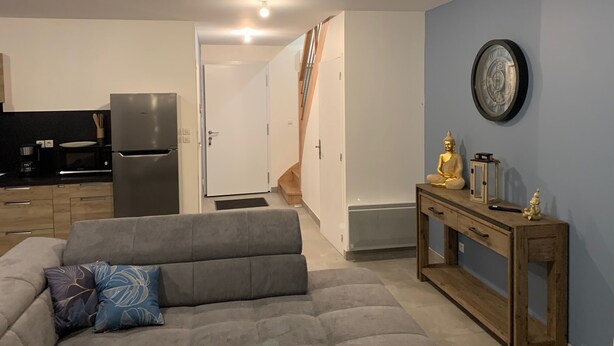 Een moderne woonkamer met een grijze bank, een houten console en een Boeddha-beeld.