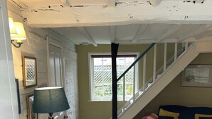 Een gezellige woonkamer met een trap, een blauwe bank, twee fauteuils en een kamerkleed met dessin.