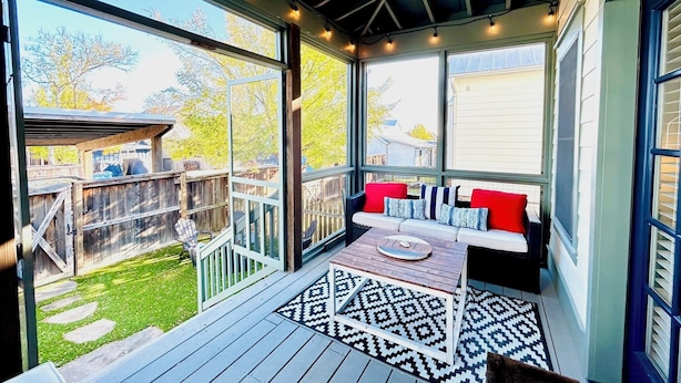 A covered porch with a seating area, a wooden deck, and a view of the backyard.
