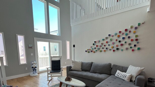 Ett rymligt vardagsrum med en grå soffa, ett litet vitt soffbord och en färgstark väggdekoration.