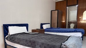 Un dormitorio con dos camas individuales, un armario de madera y un espejo.