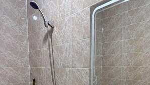 Un baño con ducha, lavamanos y espejo.