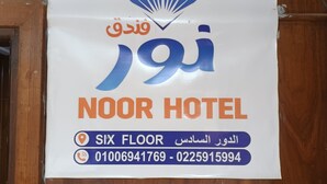 Señal del Hotel Noor que indica que tiene seis pisos y proporciona números de contacto.