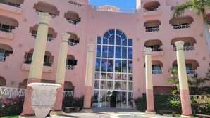 A pink building with multiple balconies, large windows, and a central entrance. - Pueblo Bonito Rose Resort & Spa - Luxury 1-bedroom Suite, right on Medano Beach! (Cabo San Lucas)