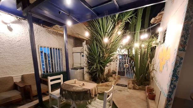 A cozy outdoor seating area with a table and chairs, surrounded by plants and decorative lights. - munay apartment (Cusco)