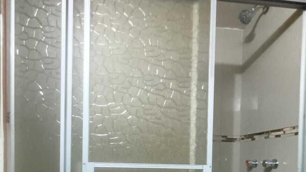 Un box de ducha con puertas de vidrio esmerilado y estructura metálica.